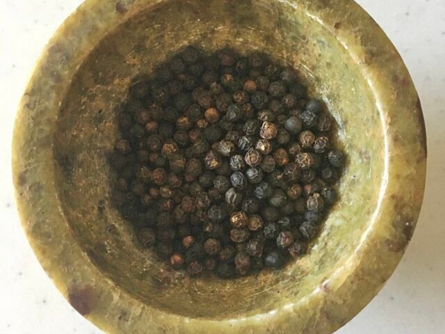 Black peppercorns in a brass bowl